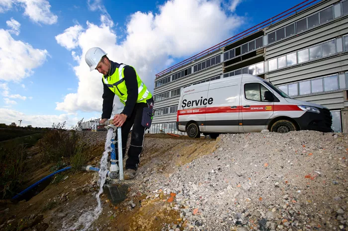 Mitarbeiter von Zeppelin Rental prüft Wasseranschluss auf Baustelle vor Containeranlage