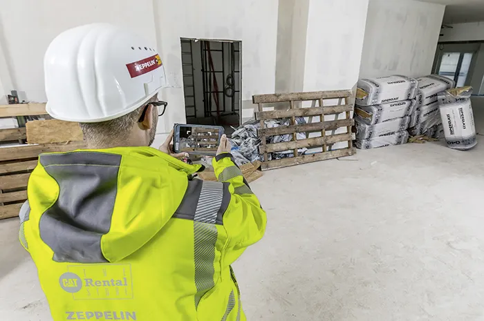 Mitarbeiter der Zeppelin Rental dokumentiert mit Smartphone Bauschutt und Baumaterialien in einem Rohbau