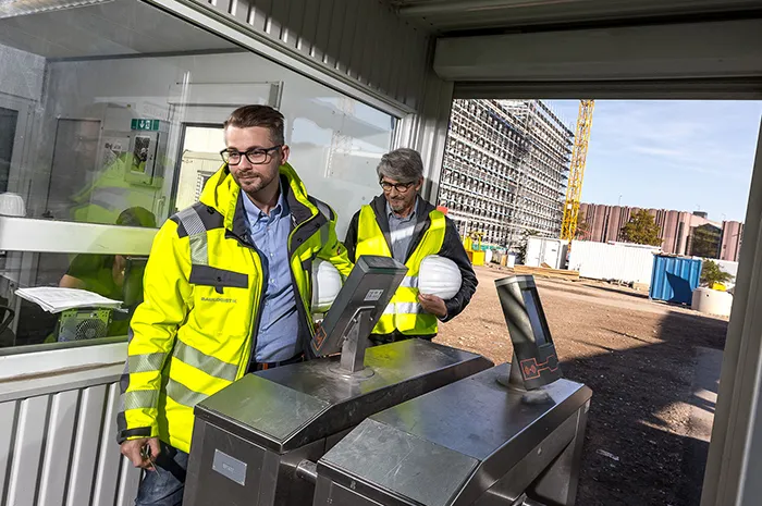 Zwei Bauleiter passieren Zutrittskontrolle auf Baustelle mit digitalem Zugangssystem