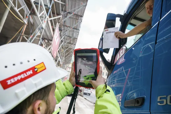 Zeppelin Rental Mitarbeiter scannt Lieferdokument mit Tablet bei digitaler Materialannahme an der Baustelle