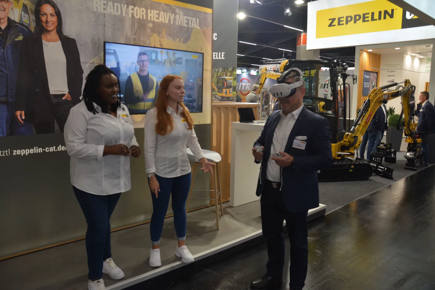 Über die Ausbildungs- und Karrieremöglichkeiten bei Zeppelin informierten Leone Schweibenz (links) und Sophia Kammler (Mitte), zuständig für Recruiting und Employer Branding bei Zeppelin, auch mithilfe von VR-Brillen. Holger Schulz (rechts), Vorsitzender der Geschäftsführung der Zeppelin Baumaschinen GmbH, nutzte an Ort und Stelle die Gelegenheit, in die virtuelle Welt einzutauchen. 