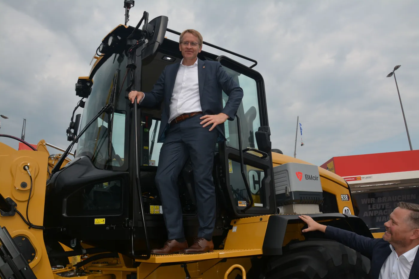 Der schleswig-holsteinische Ministerpräsident Daniel Günther (links) ließ es sich nicht nehmen, im Beisein von Holger Schulz (rechts), Vorsitzender der Geschäftsführung der Zeppelin Baumaschinen GmbH, im Cat Radlader 938 Platz zu nehmen.