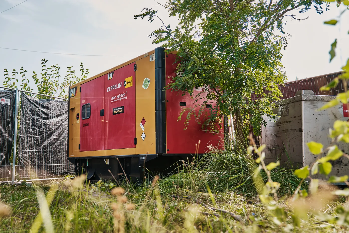 Bild von Zeppelin Rental-Aggregat, das neben einem Baum in einer Wiese steht