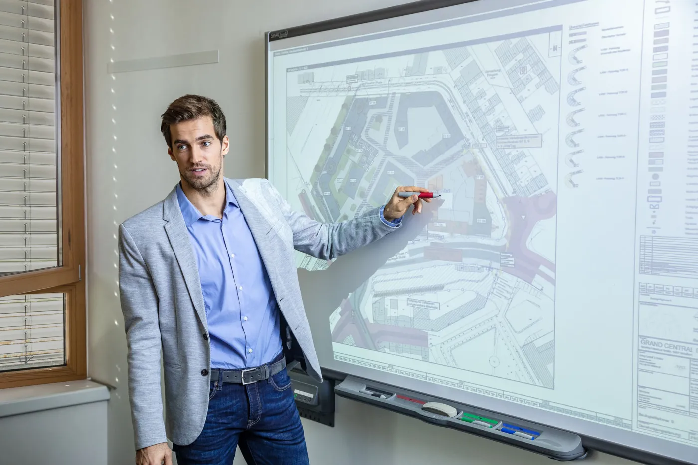 Mitarbeiter präsentiert Bauplan auf interaktivem Whiteboard im Büro